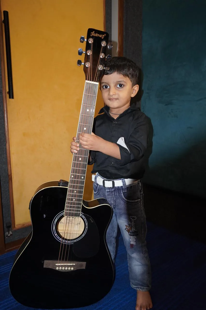 Young student holding a guitar in the studio